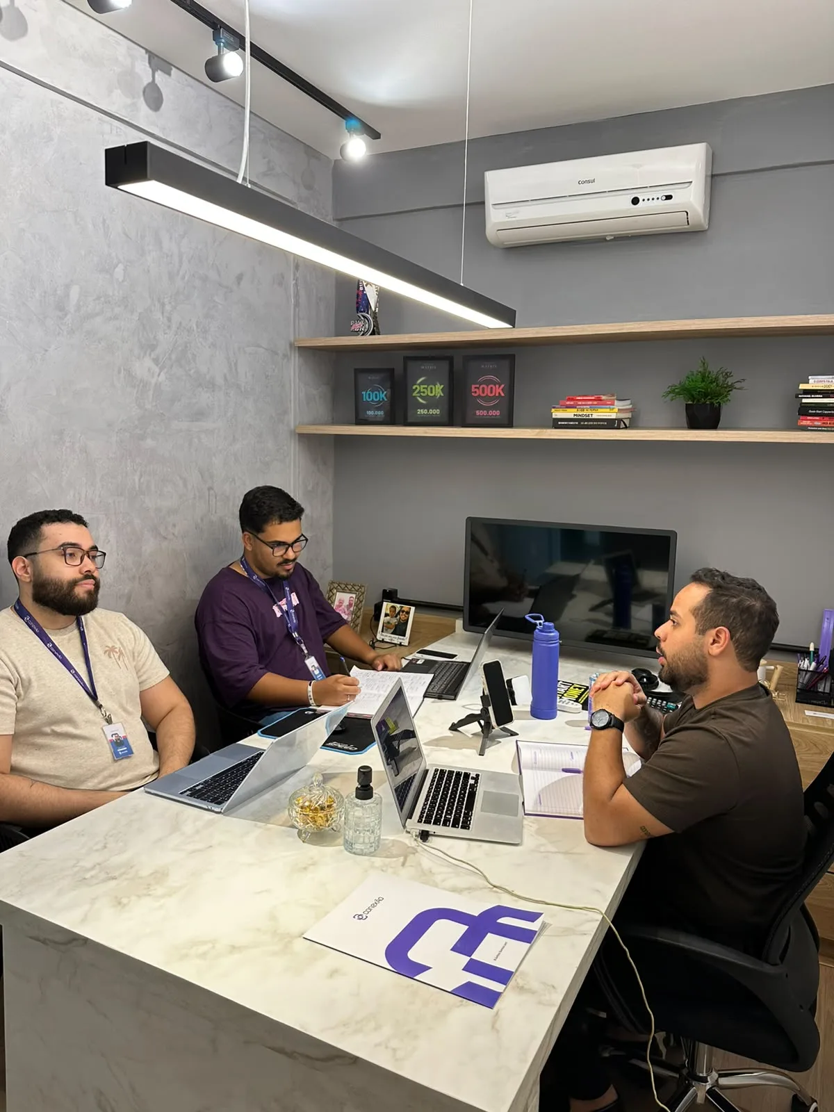 Equipe especializada da Conexão em reunião de alinhamento na sala, ao redor da mesa de mármore