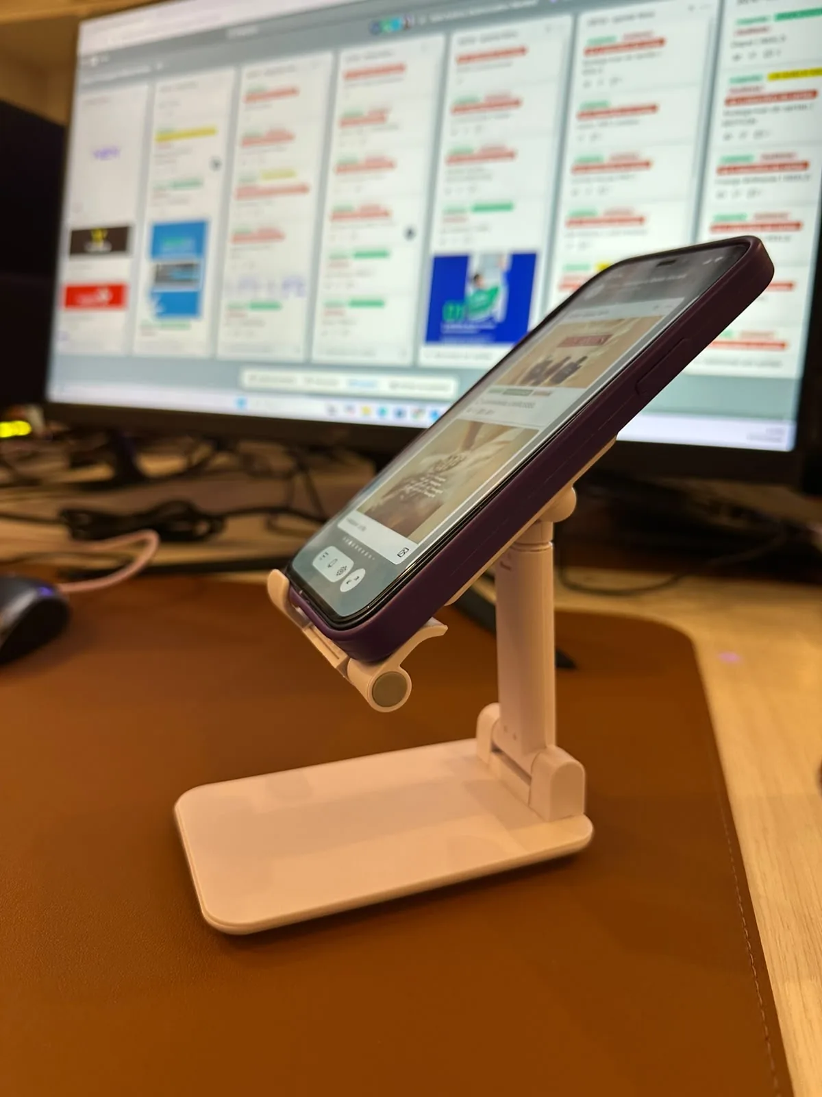 Celular com o NEX aberto num suporte de mesa, com o quadro de tarefas da equipe ao fundo